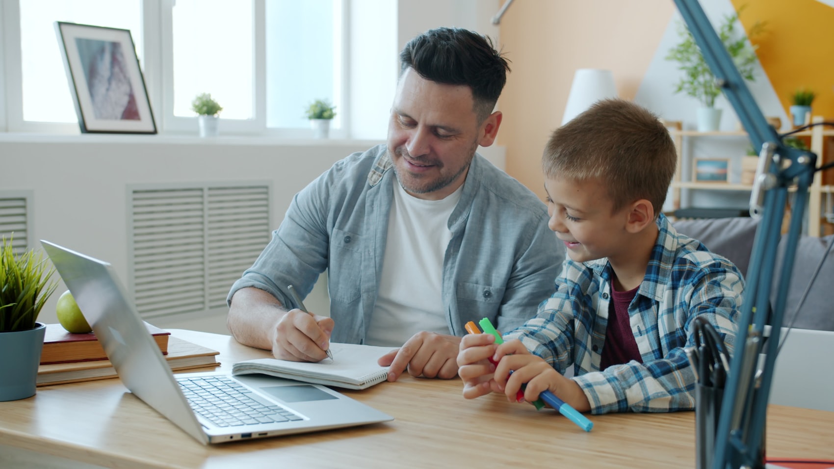 A parent and child making things together at a desk.